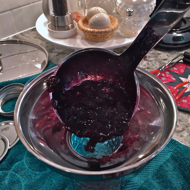 Ladling hot jam into jars using a funnel